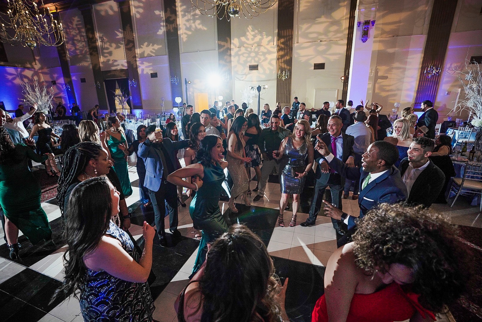 Guests in evening dress dancing at a corporate winter gala in a grand ballroom with snowflake lighting