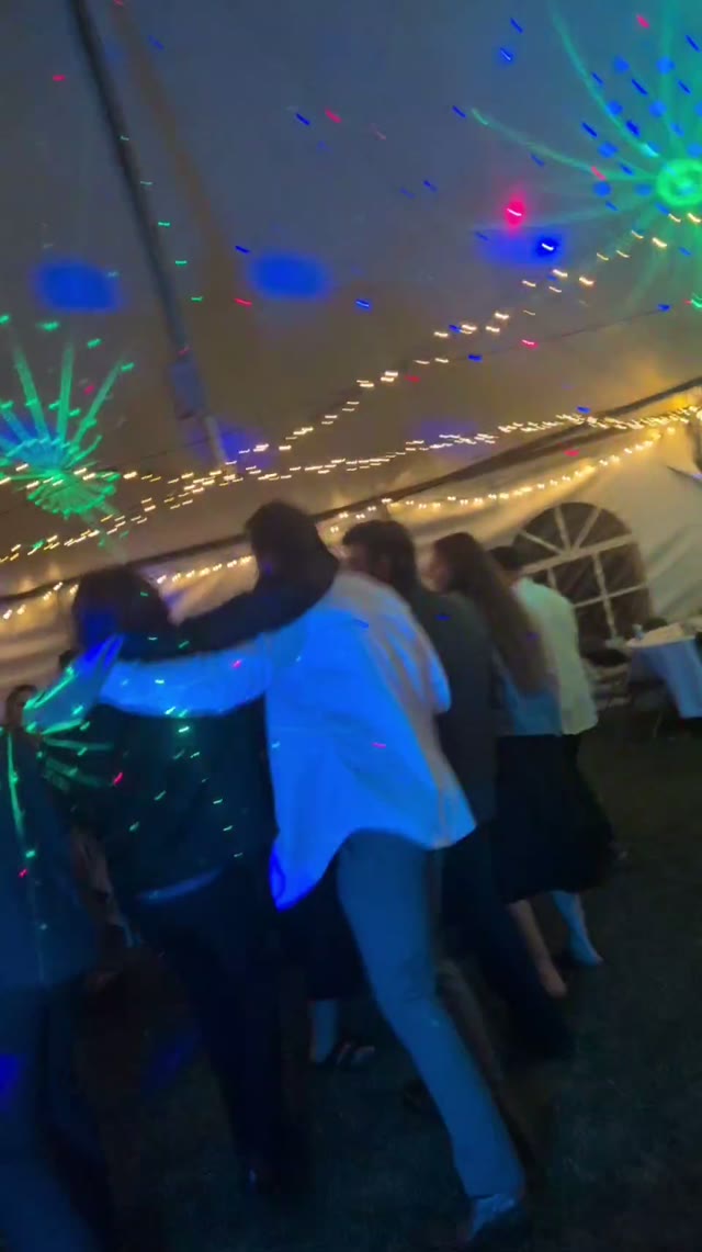 Inside a party tent strung with lights, a full dance floor under disco spots